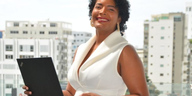 Julissa Mateo poses confidently, holding a laptop