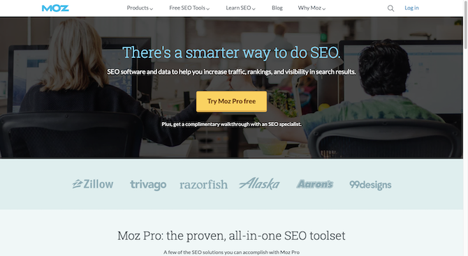 The Moz homepage has a light blue headline over a darkened hero image of two people sitting at a desk. The headline reads: “There’s a smarter way to do SEO.”