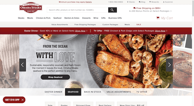 The home page for the Omaha Steaks website has a larger hero slider on it. The image we see here shows off a mixture of seafood — salmon filets, skewered shrimp, and lobster tails. The text reads: “From the ocean with Love. Sustainable, responsibly sources, and flash-frozen the moment it leaves the boat, Omaha Steaks seafood is the perfect addition to any menu”. There’s a black button beneath that reads “Shops Seafood”.