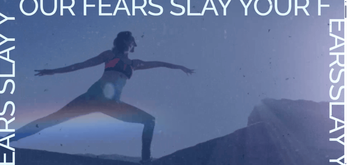 On the homepage of the website for Brett Larkin, there’s a video reel in the hero section. In this screenshot, we see Brett in the Warrior II yoga pose. Around the blue-filtered image is text that reads: “Slay your fears” over and over.