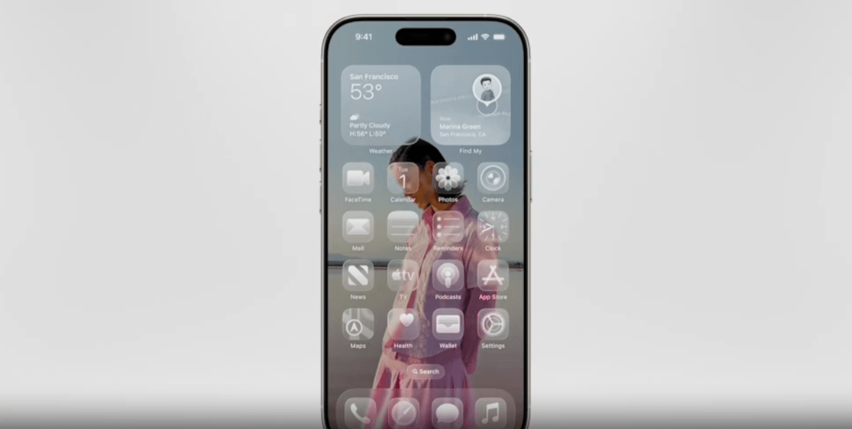 In this iPhone example for Liquid Glass, we see a woman in the home screen background. She’s wearing a pink outfit. In front of her, the screen is filled with a weather tracker, a personal info card, app icons, a search bar, and a dock at the bottom. All of these components are colorless and semi-transparent.