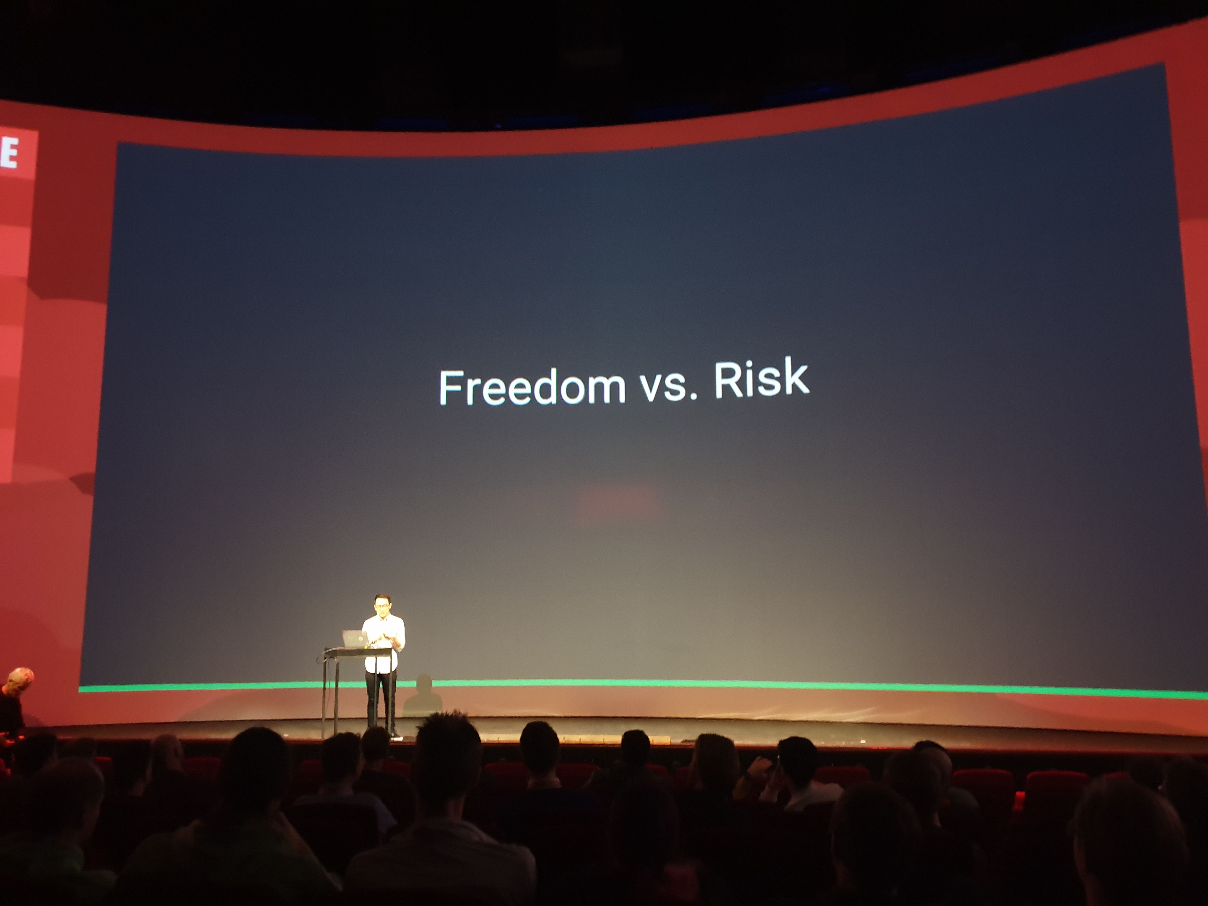 Evan You stands on stage in front of a slide that reads Freedom vs. Risk