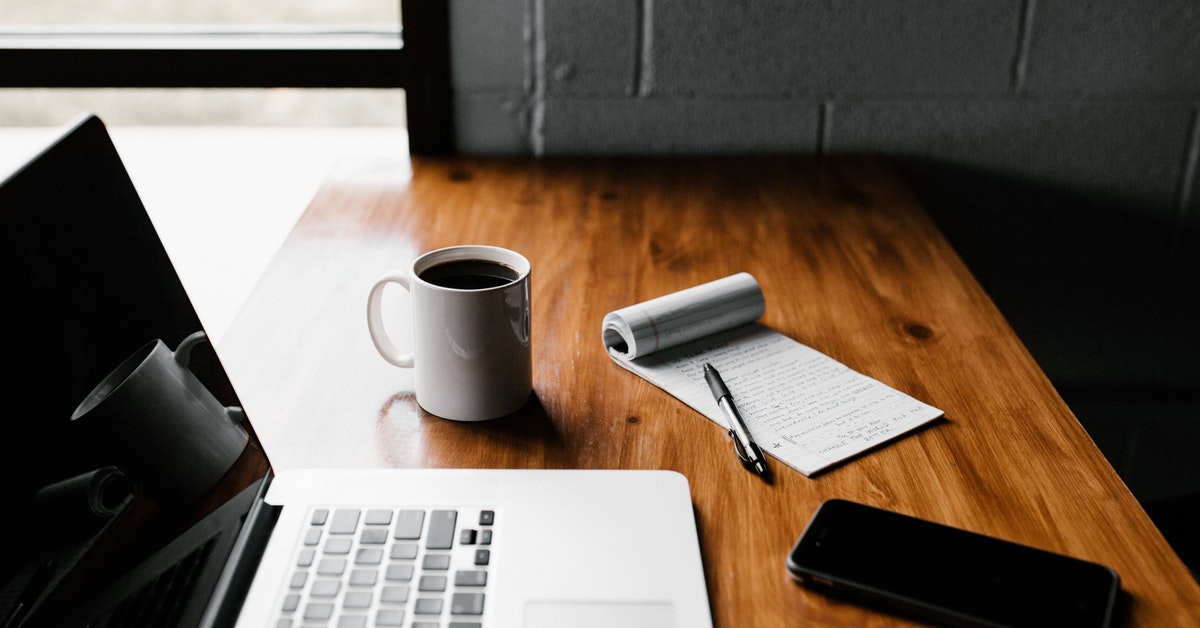 Laptop, notepad, coffee on a table