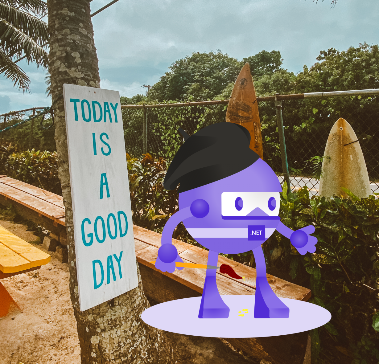 .NET MAUI mascot on a beach photo with a hand-painted sign that says: today is a good day